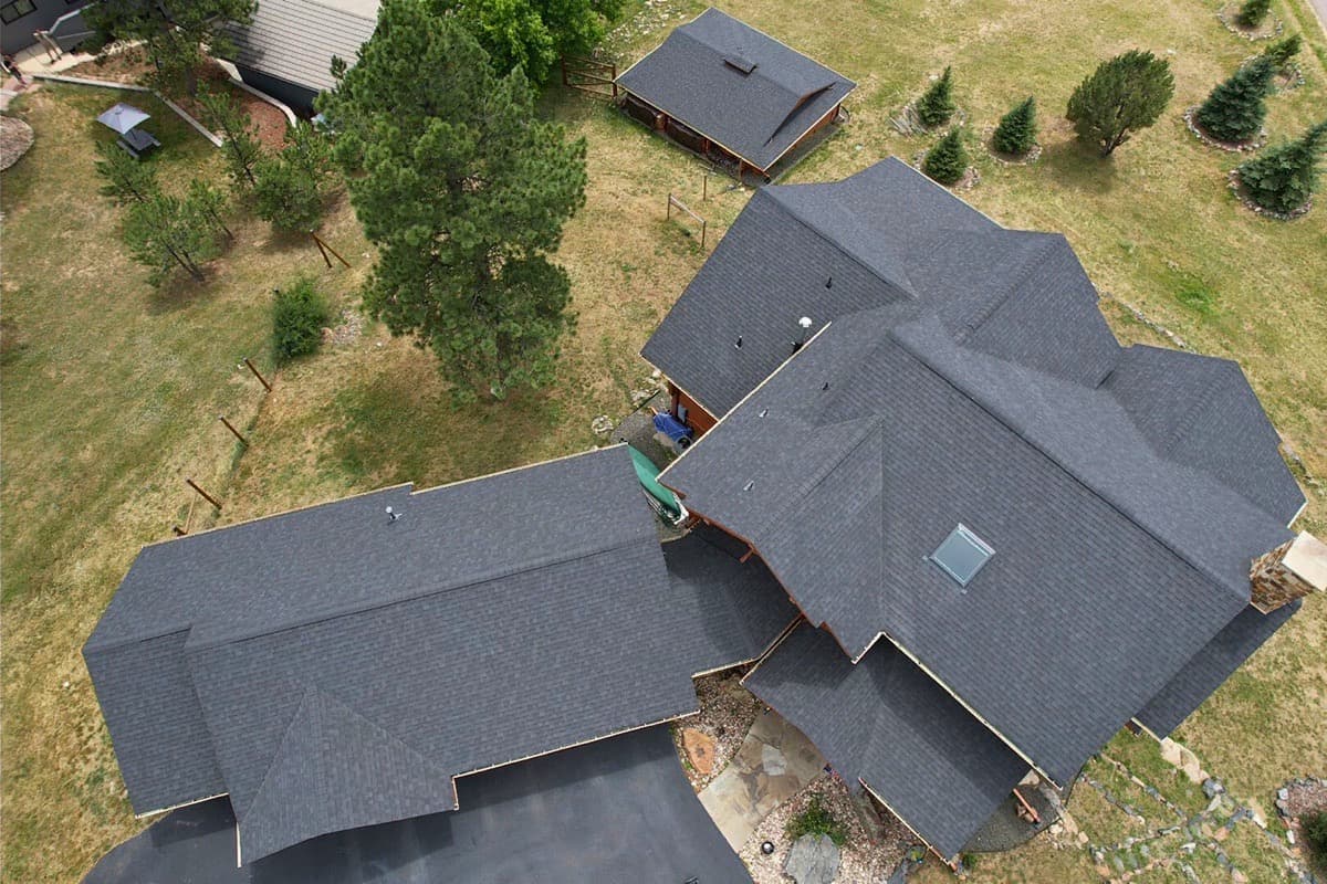 Completed charcoal shingle roof on residential home with aerial view