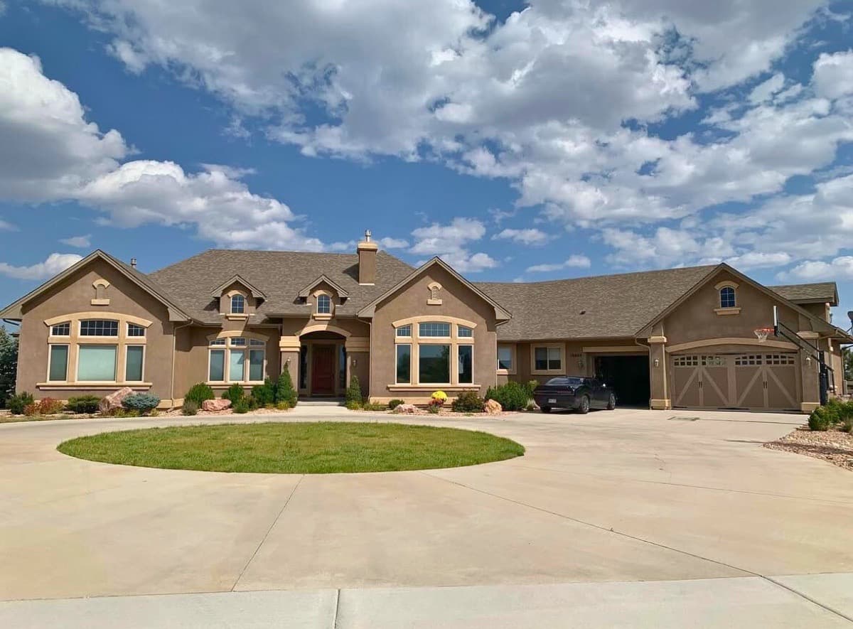 Completed shingle roof on custom stucco home with circular driveway