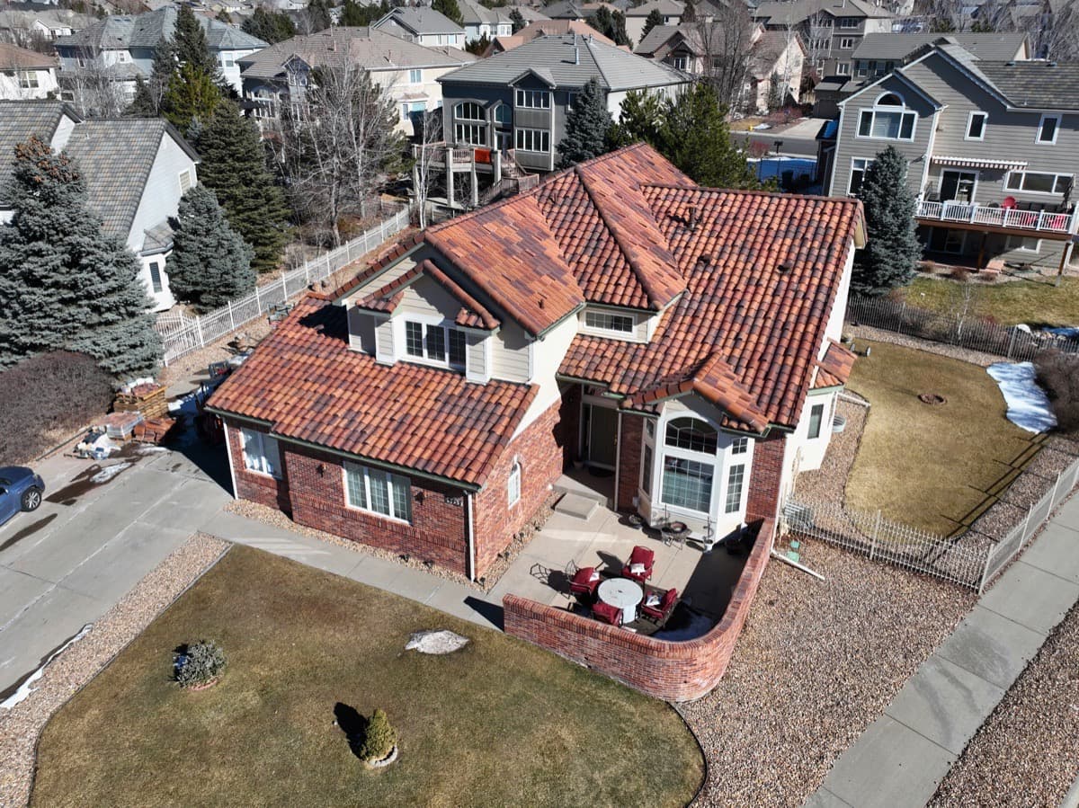 Completed clay tile roof on brick estate home with aerial view